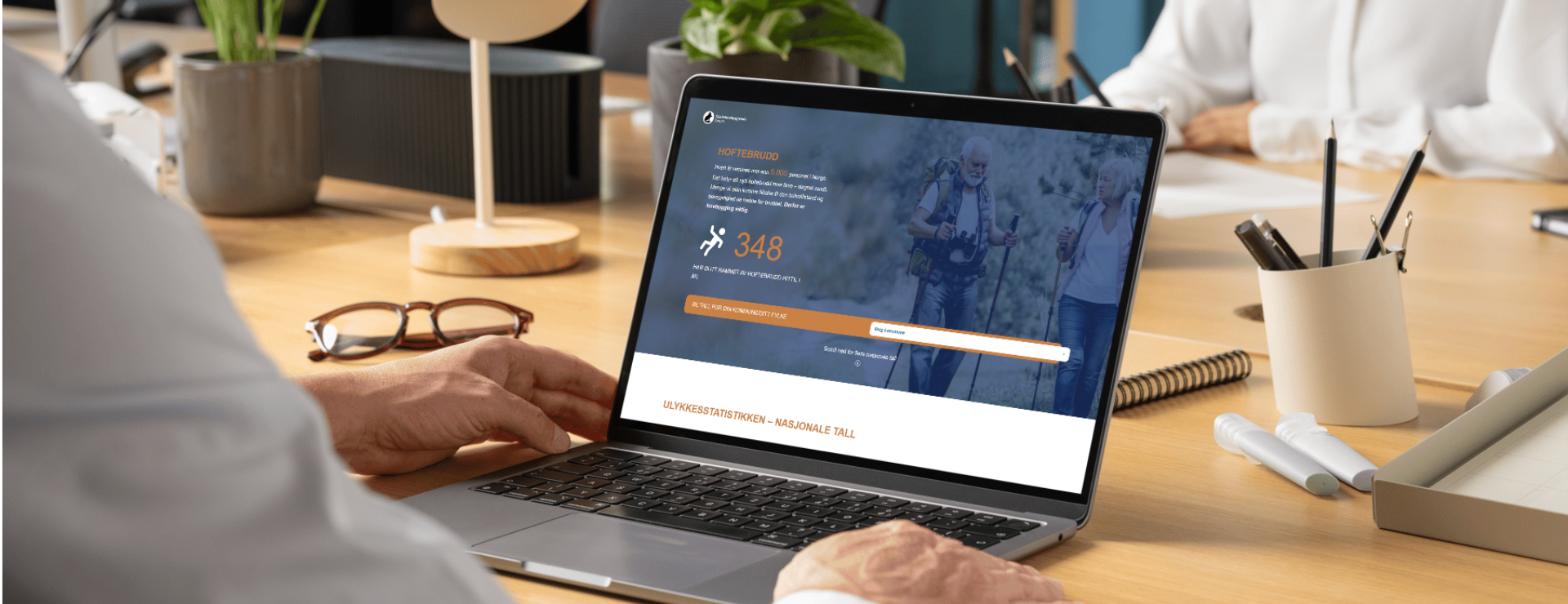 En bærbar data står på en pult. På skjermen er siden Fallbarometer for hoftebrudd åpen.
