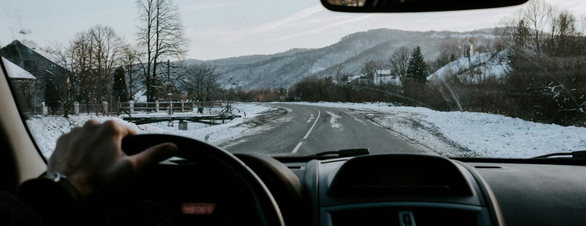 Man ser ut av en frontrute fra en bil på en bilvei om vinteren.